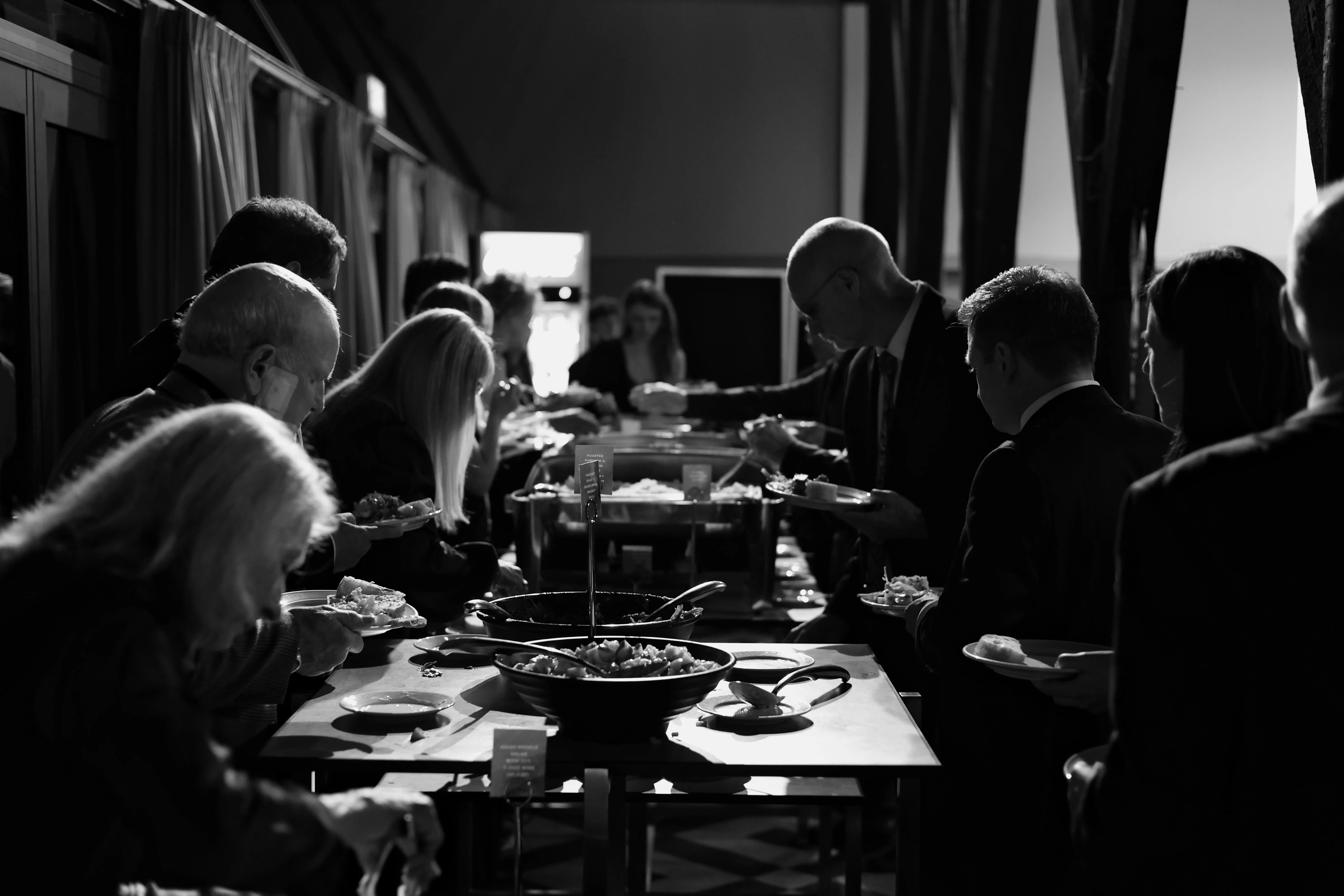 Guests serve themselves from a buffet in a black-and-white photograph