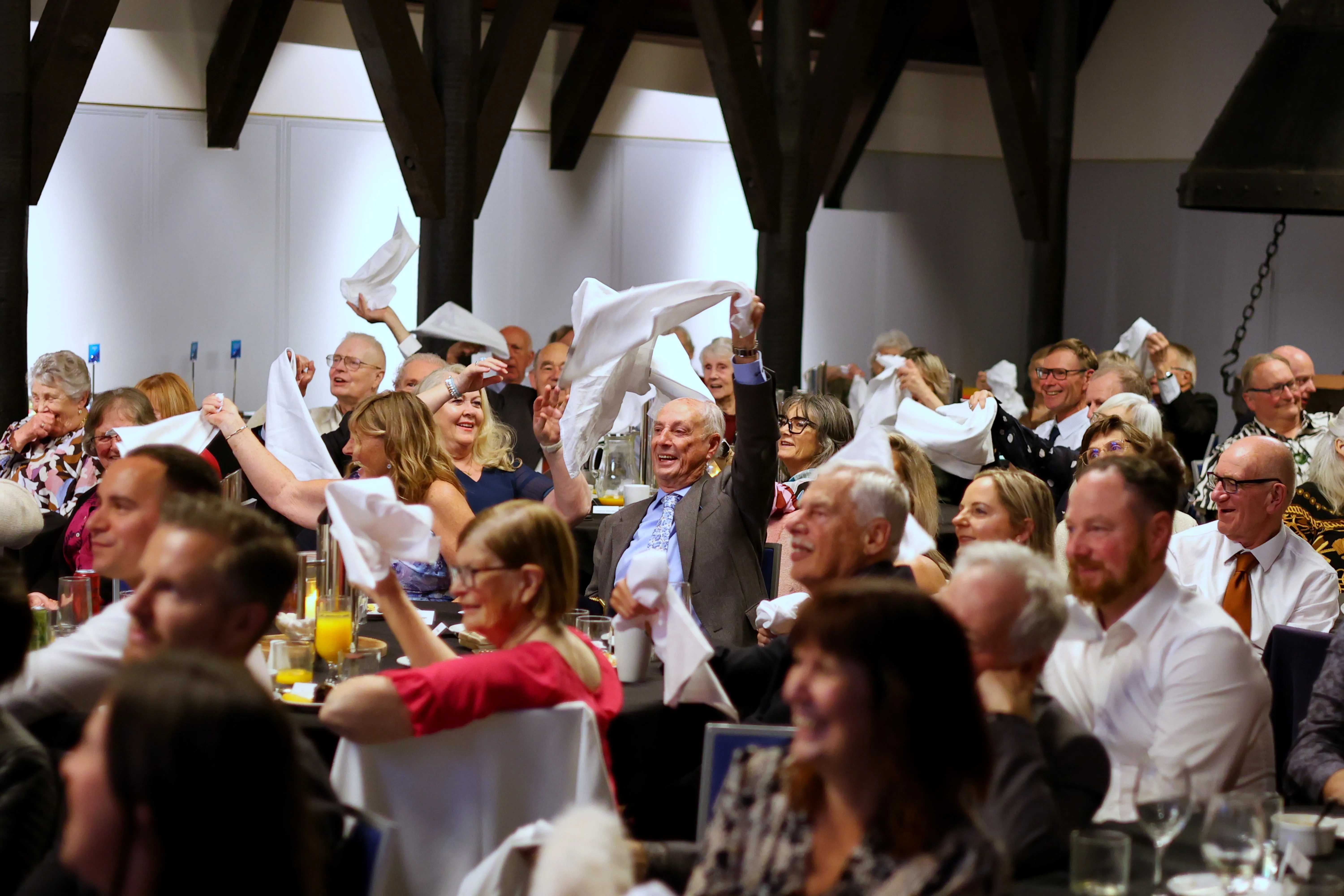 Guests wave white napkins in the air during a 75th birthday celebration