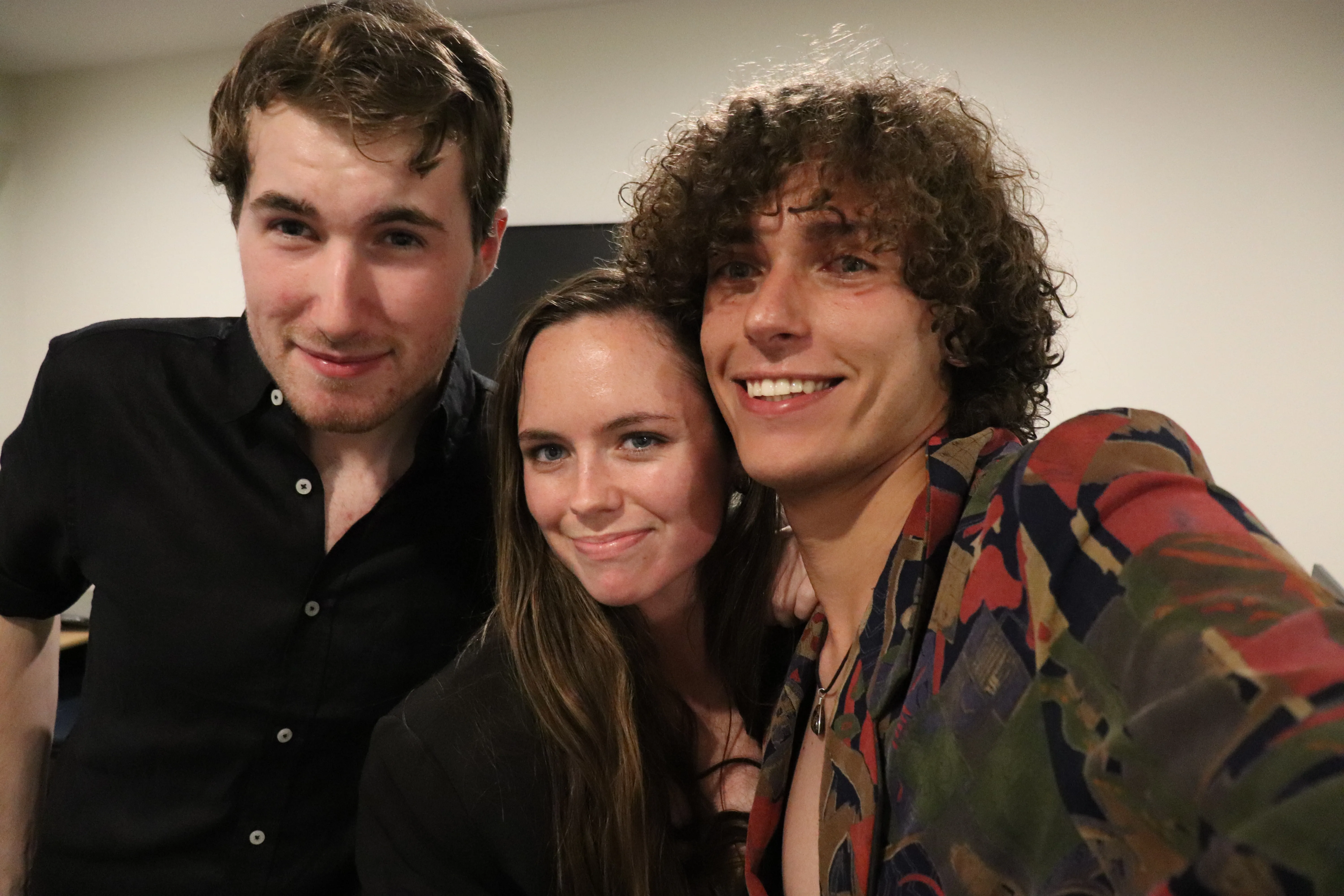Kenan-John takes a selfie with two friends posing closely beside him indoors